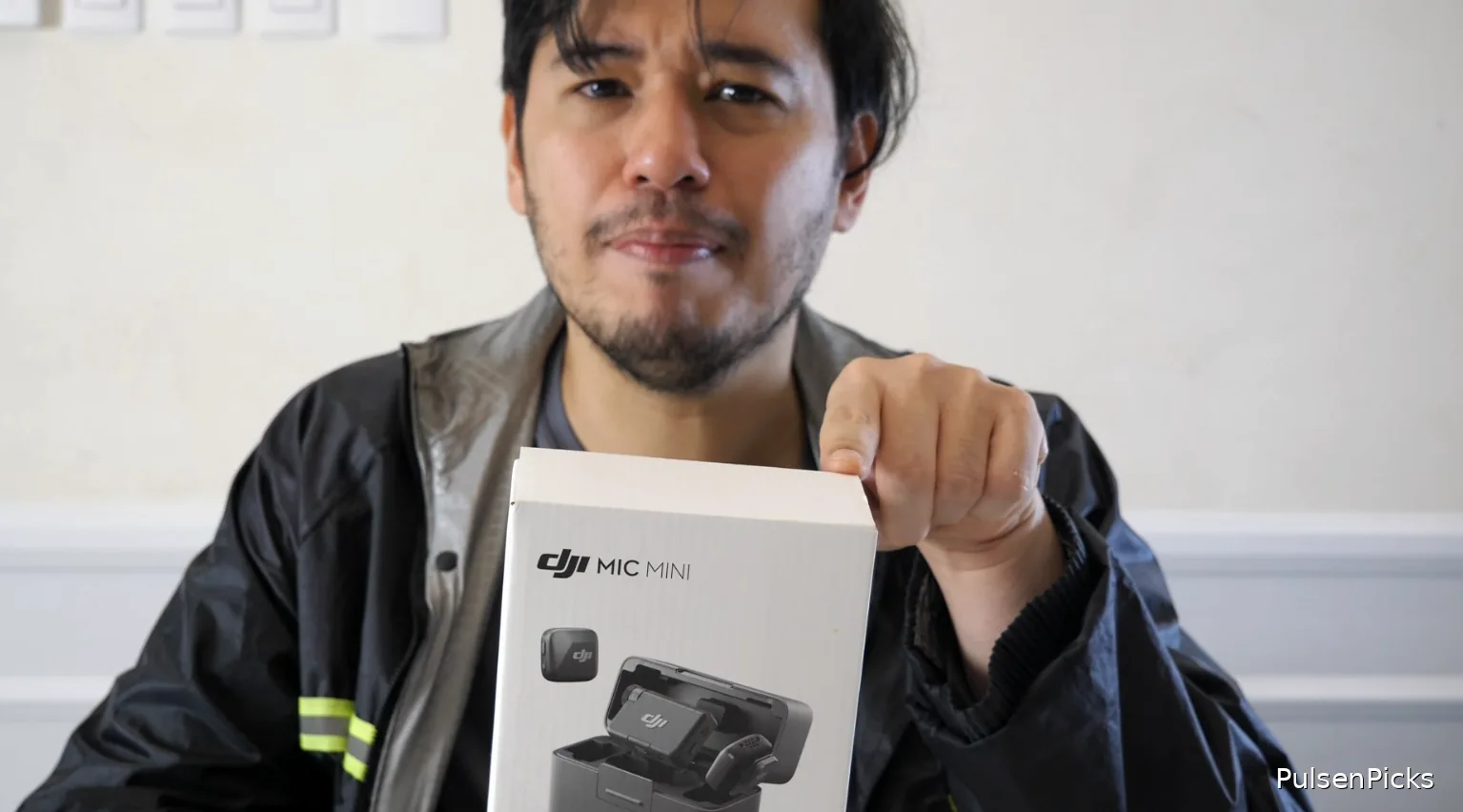 Hands-on reviewer holding DJI Mic Mini two-transmitter wireless microphone kit box