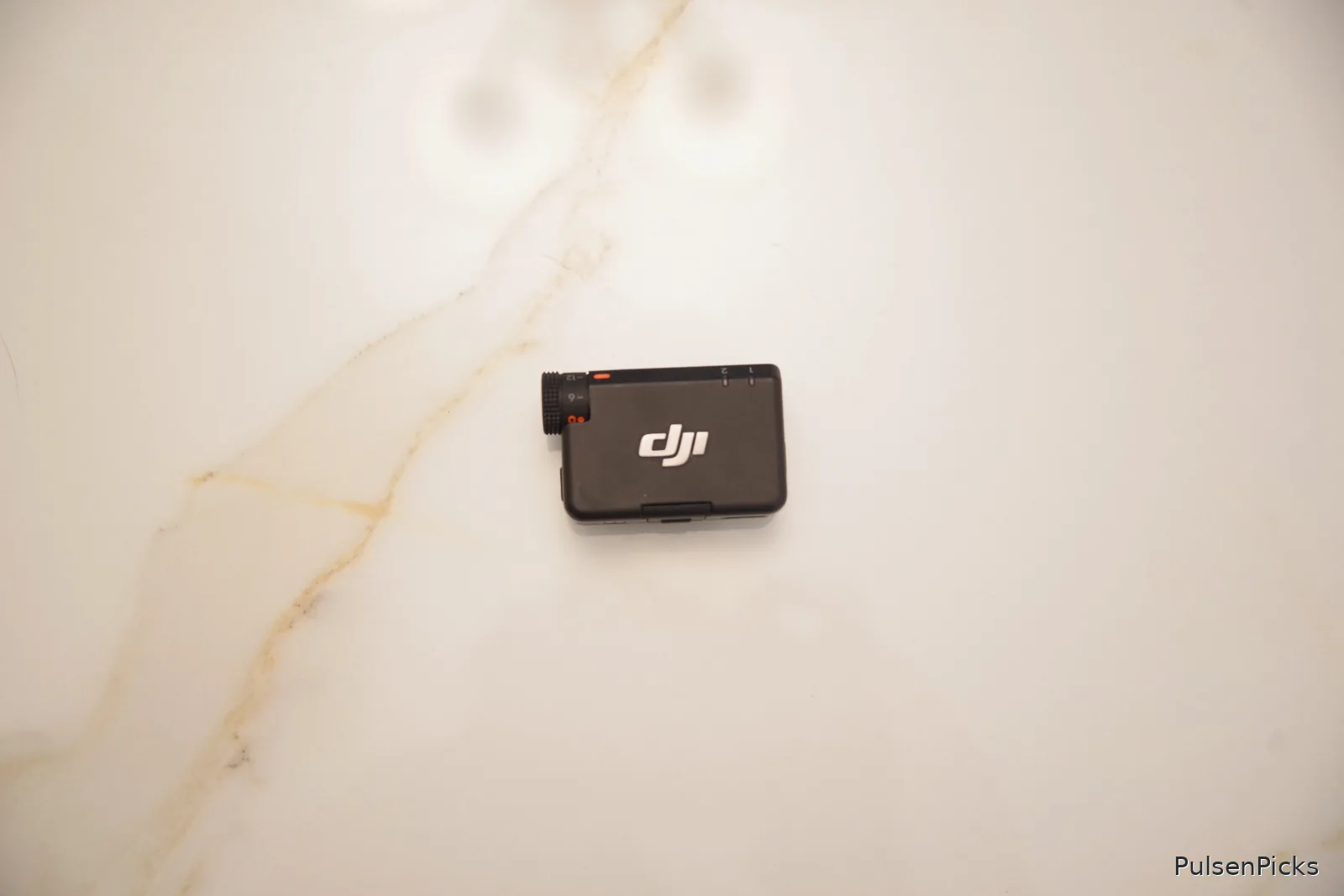 DJI Mic Mini wireless microphone receiver showing physical gain control dial