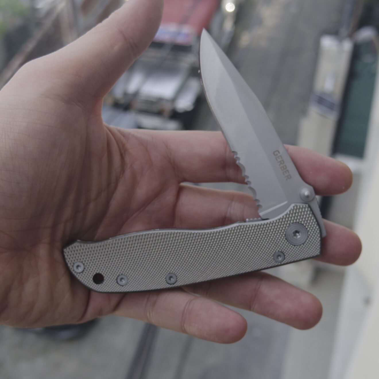 Gerber Air Ranger open partially serrated blade and textured aluminum handle resting on a hand