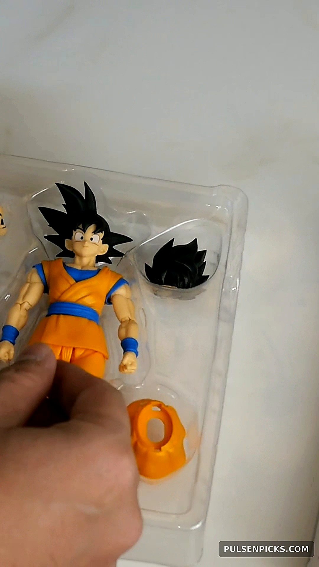 Goku DAIMA face and other included parts photographed in packaging tray