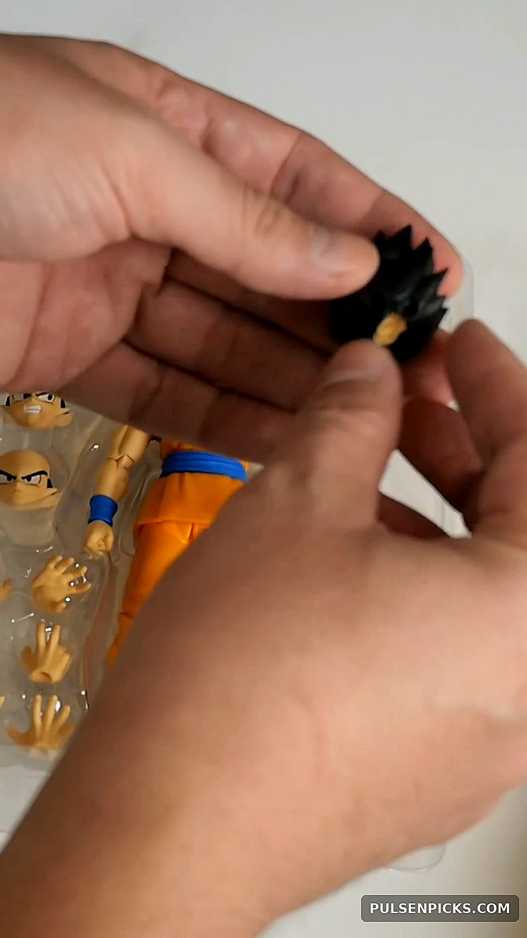 Hands handling the alternate windswept Goku DAIMA hair accessory
